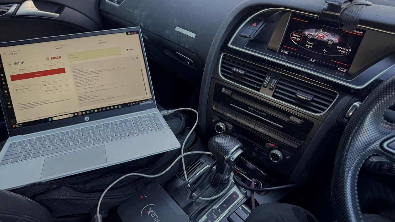 Laptop and ECU programming interface inside a car beside the centre console.